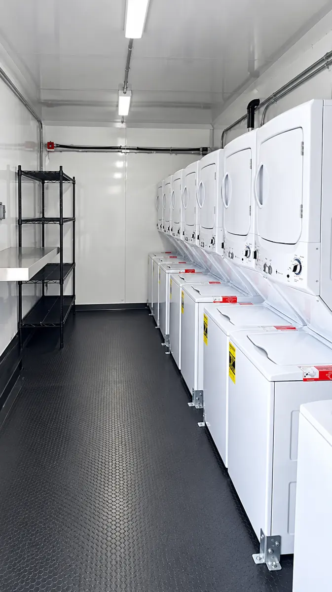 Row of stacked commercial washers and dryers inside a 30ft laundry trailer